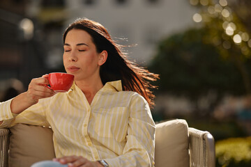 Obraz premium Woman enjoying morning coffee moment in sunlight
