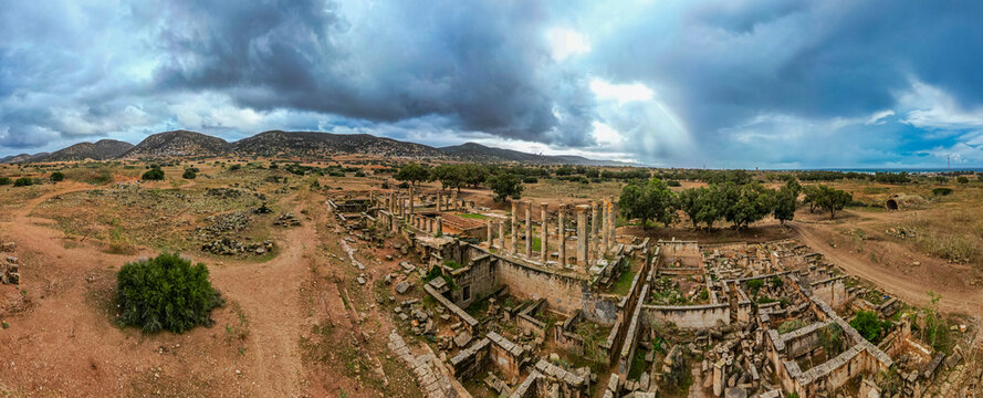 Ruins of ancient city Ptolemais in Libya show remnants of Greek architecture and landscape under cloudy sky
