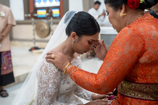 A sobbing Balinese bride is comforted by a female relative in this emotional candid photo, capturing a poignant moment from Balinese wedding traditions.