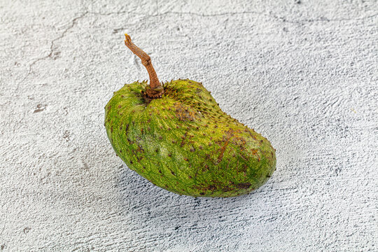 Green soursop fruit on textured white surface