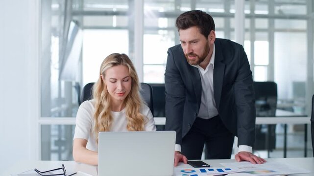 Caucasian businesswoman typing laptop businessman boss leader coming in office supporting talking to intern business woman asking advice to man ceo mentor coach corporate education internship support