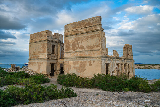 Historic coral ruins stand on Suakin Island surrounded by water and vegetation near the Red Sea coast in Sudan