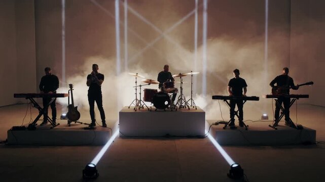 Playing band of five in studio after lighting cue for recording with drums microphone dark clothes
