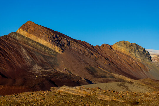 Colorful layered mountain structures under a clear blue sky in Maria, Greenland showcasing natural formations and geological features