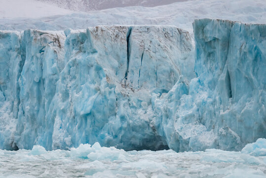 Massive glacier wall with crevasses and pale blue ice above drifting floes in Greenland's Borgvig region