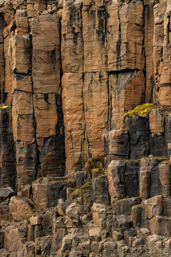 Vertical view of weathered basalt columns with fractures and moss in Borgvig, Greenland creating unique natural patterns