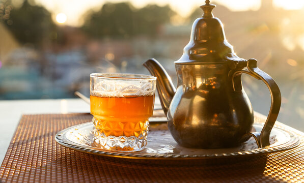 Mint tea served in a silver teapot with a glass in Morocco during sunset