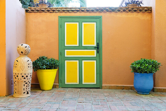Bright door and decorative pots in an exotic garden with cacti in Marrakesh, Morocco during daylight hours