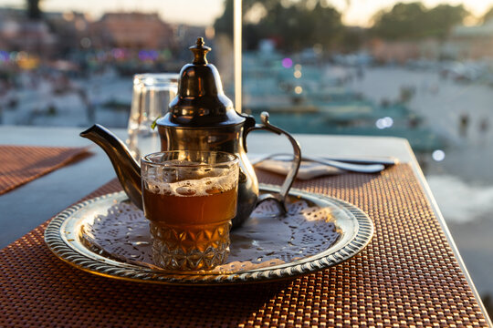 Enjoying traditional mint tea from a teapot in Morocco as the sun sets over the bustling market