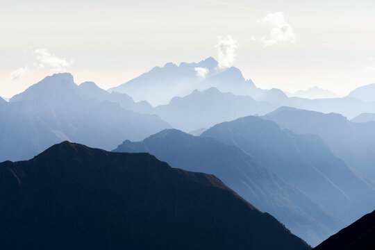 Mountains rise in layers in the Adamello park of Brescia province with different shades of blue in Lombardy, Italy