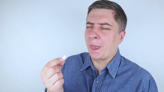 Man suffering from phagophobia struggling to swallow pill. Caucasian male looking anxious and scared before taking medication, experiencing fear of choking or swallowing difficulties.