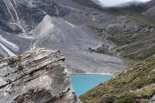Rocky ridge overlooks turquoise Milk Lake in Yading Nature Reserve in Sichuan China with scree slopes in background