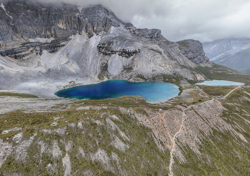 Vibrant glacial lakes below grey cliffs on Tibetan Plateau in Yading National Park during daytime
