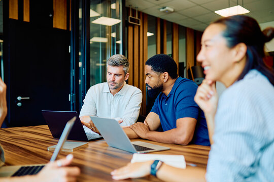 Multicultural professional colleagues discussing work, sharing ideas, and brainstorming during a business meeting in a contemporary workspace