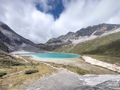 Visit to turquoise milk lake in high-altitude grassland of Sichuan with rocky slopes in Yading National Park