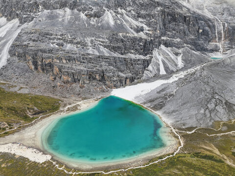 Turquoise Milk Lake with grey cliffs and snowfields in Yading National Park, Daocheng, Sichuan, China