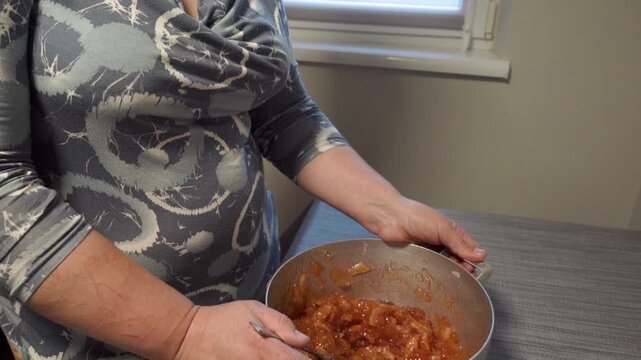 Woman holding a pot with homemade apple jam or fruit filling , Preparing homemade apple jam or confit in the kitchen close up