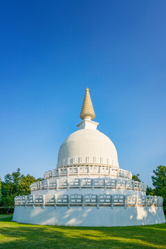 White Peace Stupa dome with golden spire in bright sky at Zalaszanto Hungary