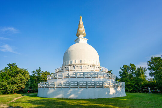 White dome Buddhist sanctuary with golden spire in Zalaszanto under sunny blue sky