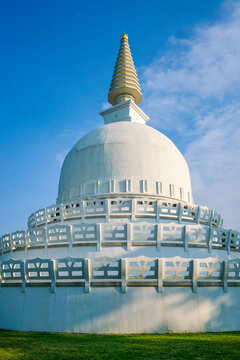 White Peace Stupa dome in Zalaszanto Hungary under sunny blue sky with golden spire standing tall during bright daylight hours