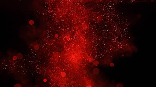 Red particles and glowing bokeh dispersing in water on black background.