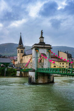 Scenic view of Seyssel village featuring a church, historic bridge, and cloudy sky over the Rhone river in France