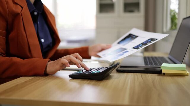 Businesswoman calculating finances while holding a chart report in modern office