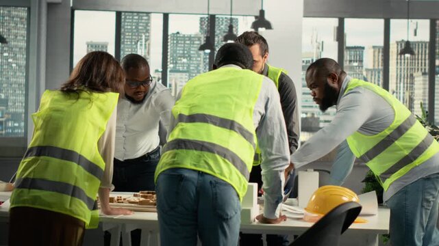 Architects and developers consult on an urban master plan inside a architecture workspace, combining site plans and project notes while they coordinate development priorities for city planning.