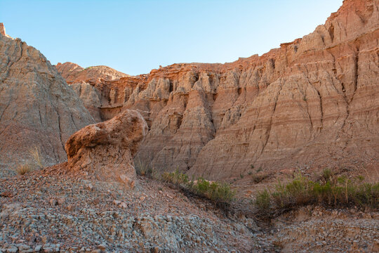 Eroded rock spire and sediment layers show geologic features along dry wash near Notch Trail in Badlands National Park