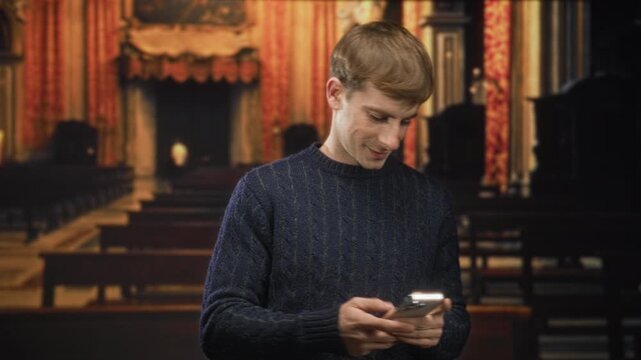Man holding smartphone and glancing sideways with a slight smile against an ornate theater backdrop in a studio; quiet contemplation.