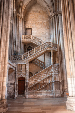 Spiral staircase inside a historic church with wooden railings and stone walls in Rouen, France