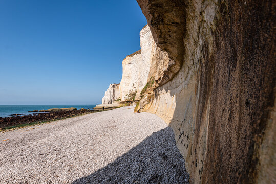 Walking path along chalk cliffs by the sea with blue sky and distant ocean view in Normandy, France