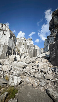Abandoned marble quarry with towering rock walls beneath clear blue sky