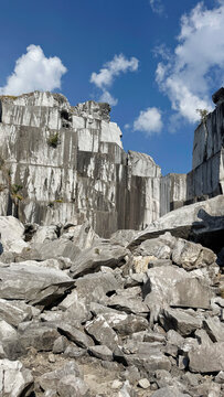 Abandoned marble quarry with towering rock walls beneath clear blue sky