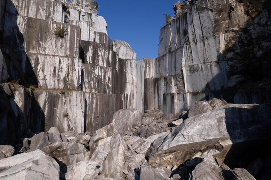 Abandoned marble quarry with towering rock walls beneath clear blue sky