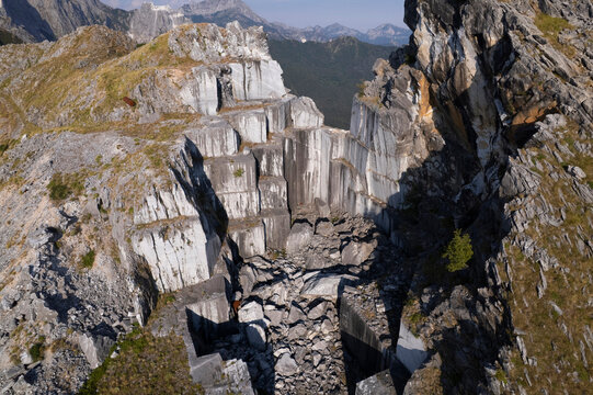 Abandoned marble quarry with towering rock walls beneath clear blue sky