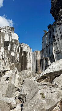 Abandoned marble quarry with towering rock walls beneath clear blue sky