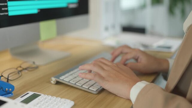 Businesswoman hands typing on a keyboard analyzing financial data on a monitor