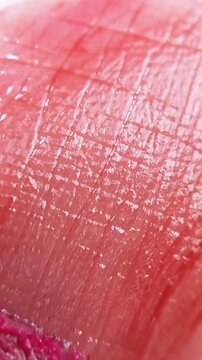 Close up of glossy pink lip skin being applied with lip tint or lipstick using a brush. Shiny finish, beauty makeup concept for lip care product.