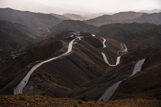 Winding mountain road cuts through the landscape of High Atlas Mountains in Morocco during evening light