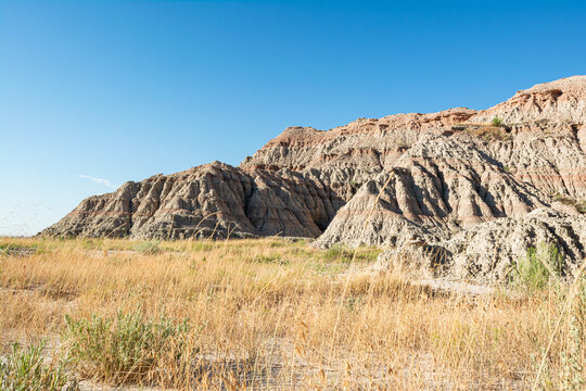 Badlands ridges and prairie grasses stretch under clear skies in South Dakota National Park