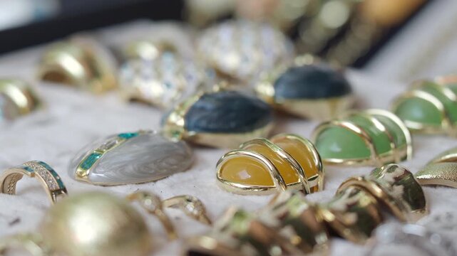 Macro close up of vintage gold jewelry with colorful gemstones and elegant rings displayed on white velvet tray