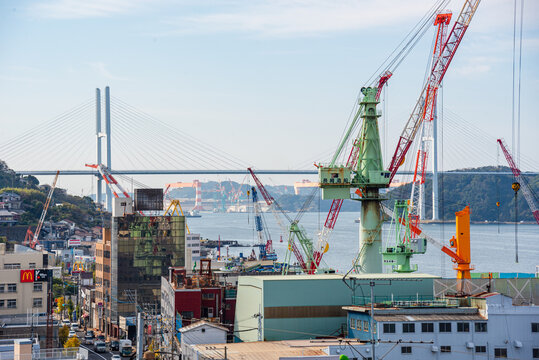 View of Nagasaki Port showing shipyard cranes and Megami Bridge in the distance amidst Japan's maritime activity