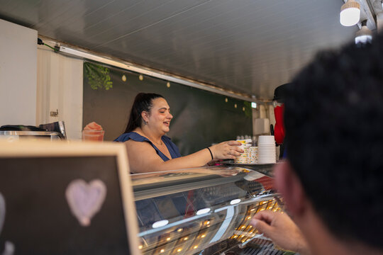 Woman vendor smiling serving customer in food truck