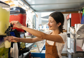 Fototapeta premium Young woman serving refreshing frozen lemonade drink at food truck