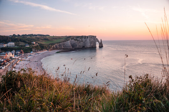 View of Etretat beach and the Aval Arch at sunset from the cliffs above the village in Normandy, France