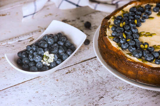 Blueberry cake, fresh blueberries on white wooden table in kitchen setting