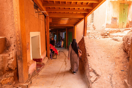 Woman walks through narrow adobe passage in old ksar of Tinghir, highlighting traditional Saharan architecture details
