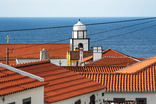 Red-tiled rooftops and church tower above the Atlantic Ocean in Faja Grande on Flores Island in the Azores, Portugal