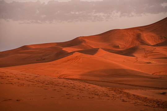 Red sand dunes in the desert display natural textures and patterns under a muted sky in Morocco's landscape